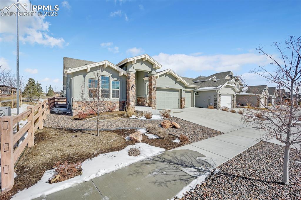Image 43 of 45: View of front of property featuring a garage, driveway, stone siding, fence