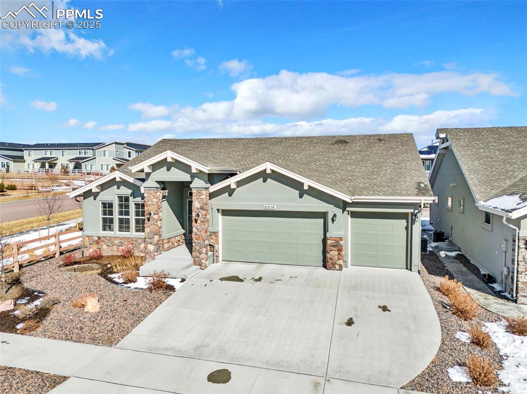 Image 44 of 45: View of front facade with stone siding, an attached garage, a residential v