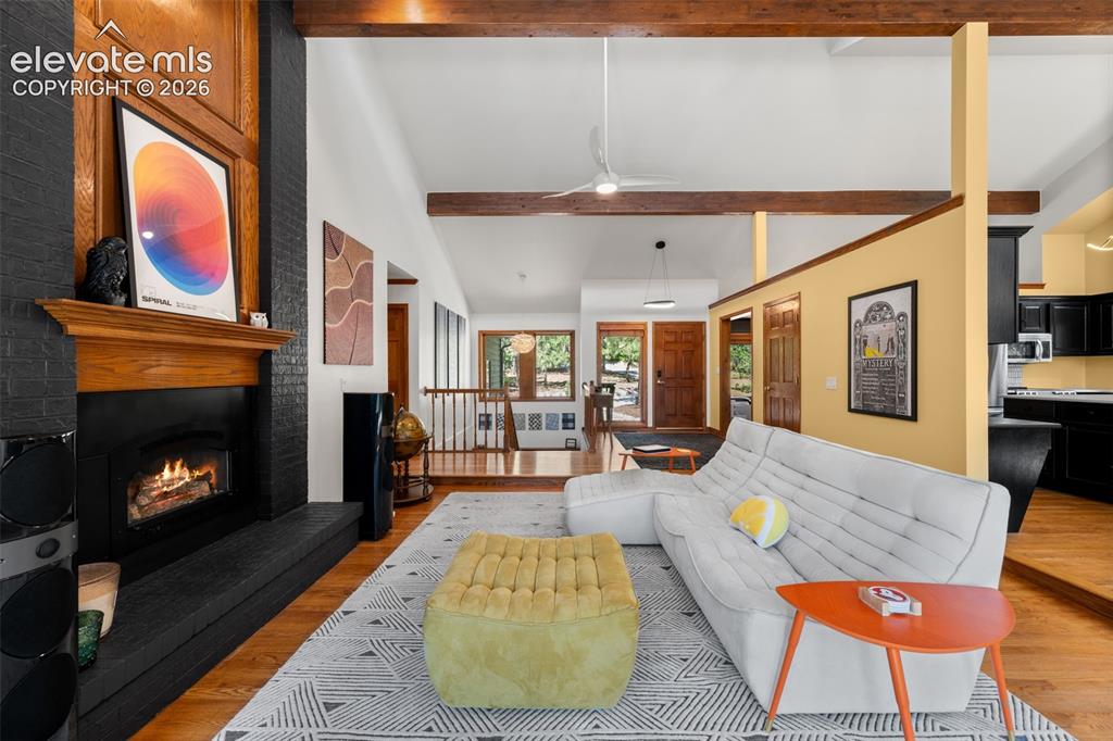 Image 10 of 47: Spacious living area featuring a black brick fireplace with a wood mantel,