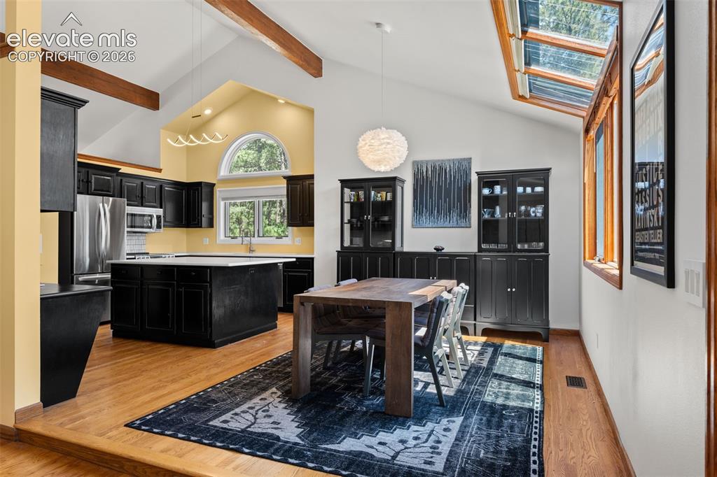 Image 11 of 47: Vaulted ceilings featuring exposed wood beams, wood-finish flooring, black