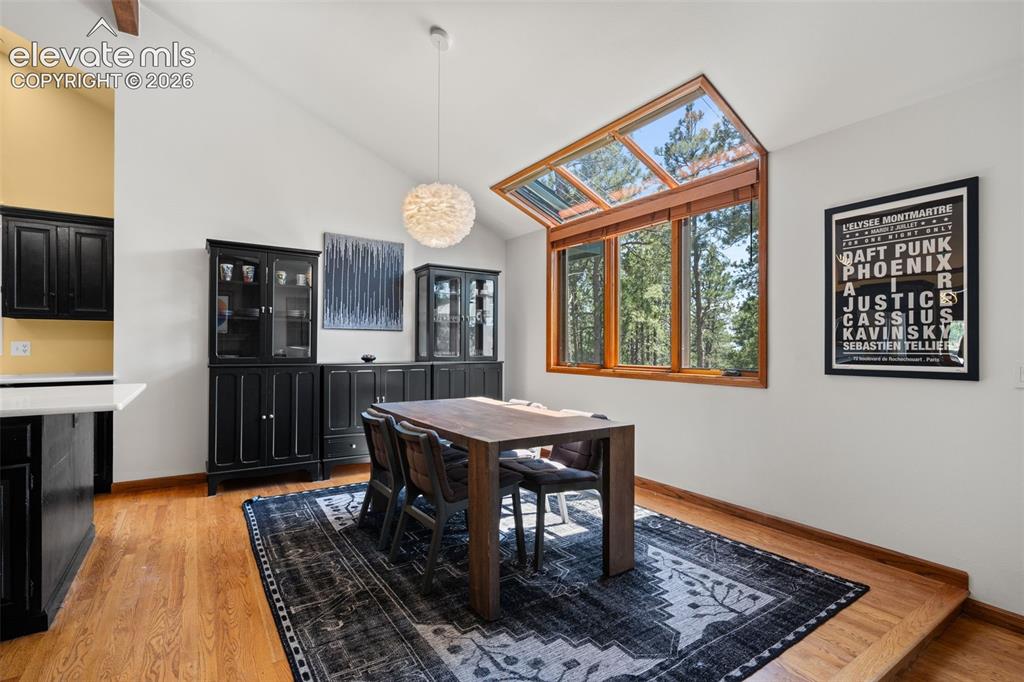Image 12 of 47: Vaulted ceiling dining area featuring wood-finish flooring and extensive wi