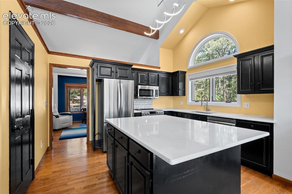 Image 13 of 47: Kitchen featuring vaulted ceilings with exposed wood beams, a large arched