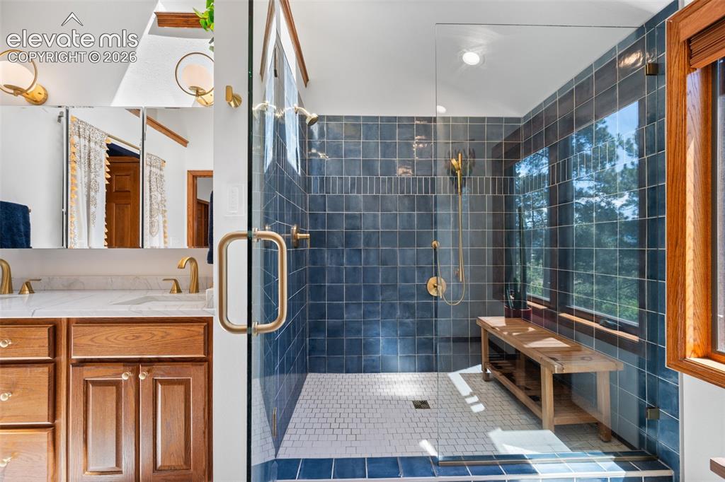 Image 23 of 47: Spacious glass-enclosed shower with blue subway tile surround, white mosaic