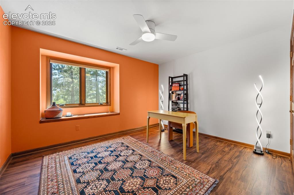 Image 27 of 47: Spacious room featuring wood-finish flooring, a large window with a wood fr