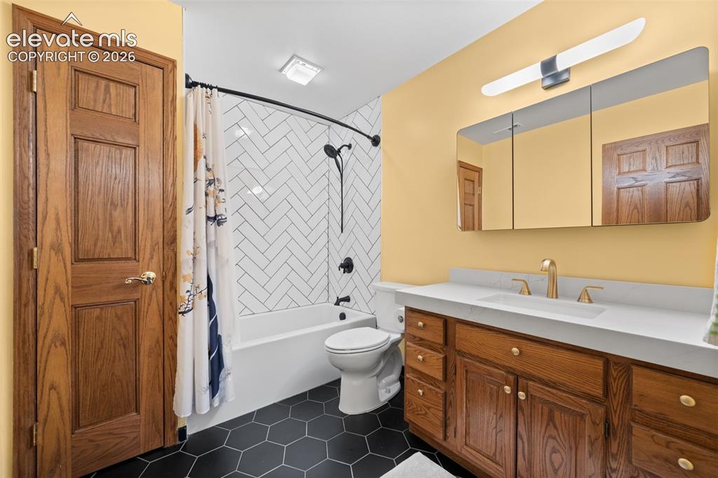 Image 28 of 47: Bathroom featuring a single vanity with wood cabinetry, a white countertop,