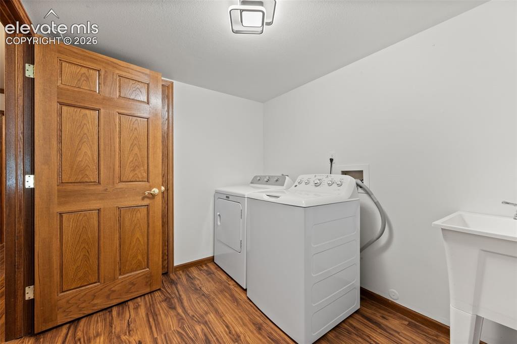 Image 29 of 47: Dedicated laundry room featuring wood-finish flooring, white walls, and a u