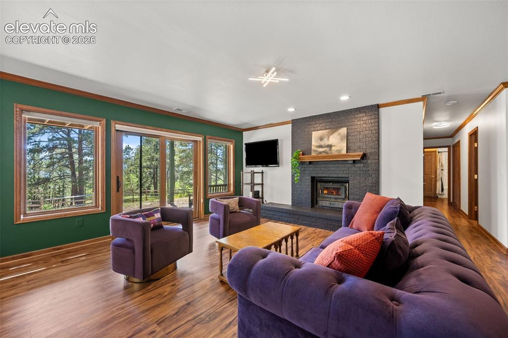 Image 32 of 47: Spacious living area featuring wood-finish flooring, a contemporary firepla