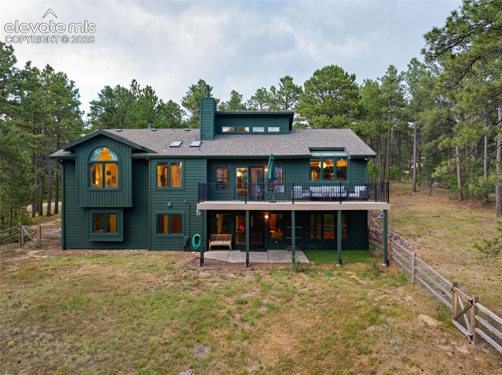 Image 35 of 47: Multi-level residence featuring a deep green exterior, a second-story deck