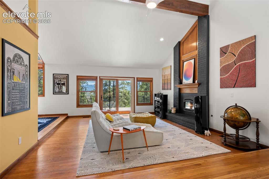 Image 7 of 47: Vaulted living space featuring a black brick fireplace with a wood mantle,