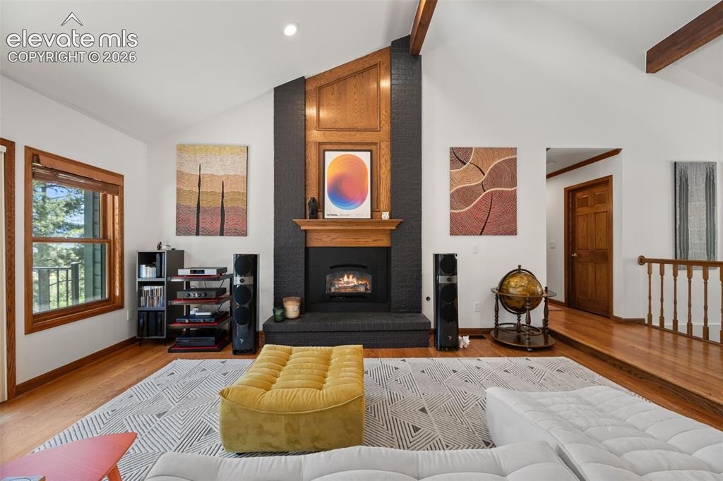 Image 8 of 47: Vaulted ceiling living space featuring a black brick fireplace, wood mantel