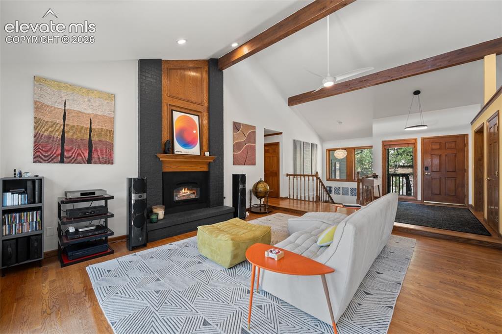 Image 9 of 47: Living area featuring vaulted ceilings with exposed wood beams, a fireplace