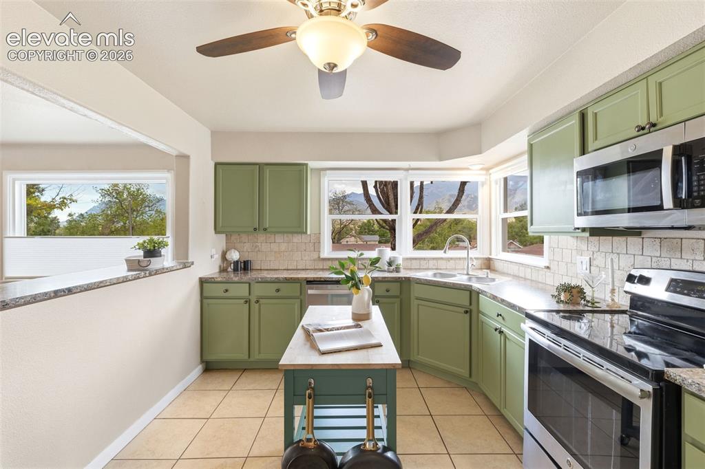 Image 11 of 48: Kitchen featuring sage green cabinetry, stone-finish countertops, and a til