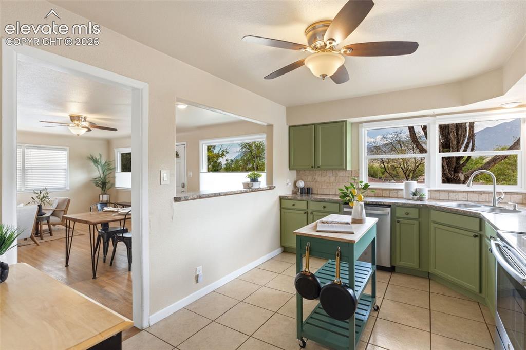 Image 12 of 48: Kitchen featuring green cabinetry, tile flooring, a stainless steel dishwas