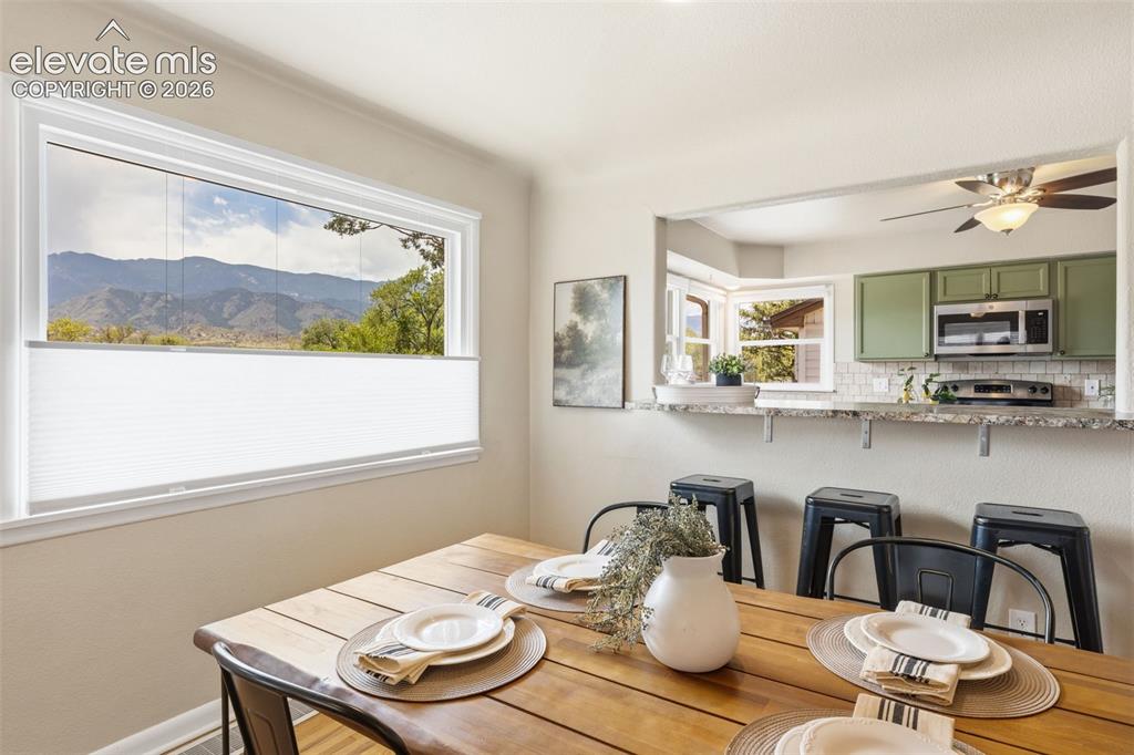 Image 15 of 47: Dining area featuring a wood-finish table, a large window with mountain sce