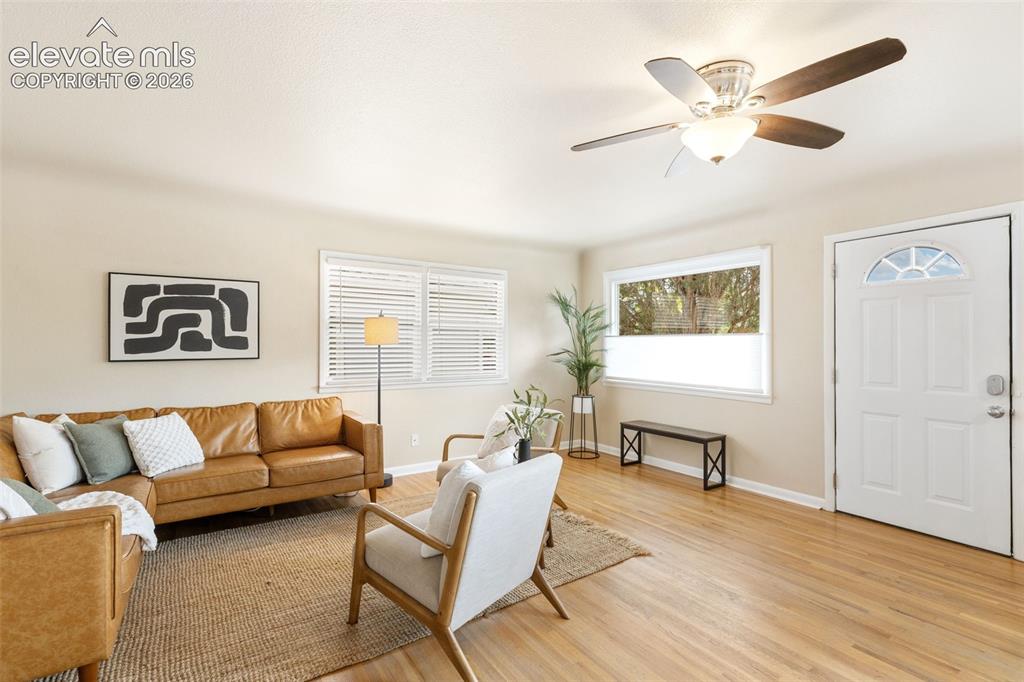 Image 16 of 47: Living space featuring wood-finish flooring, multiple windows with blinds,