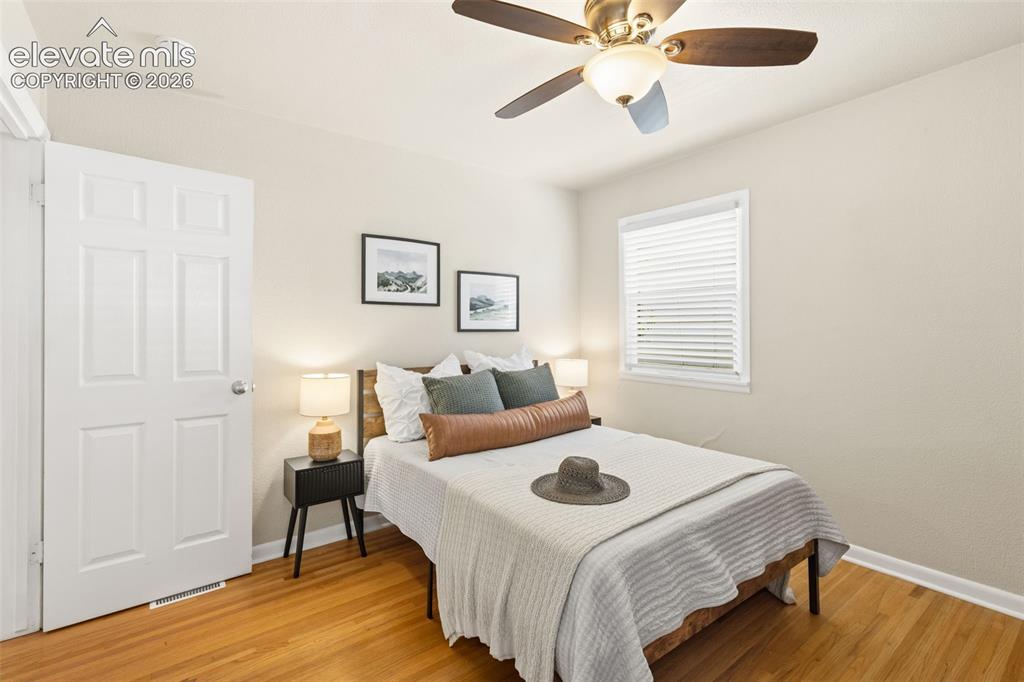 Image 22 of 47: Bedroom featuring hardwood flooring, a white six-panel door, and a window w