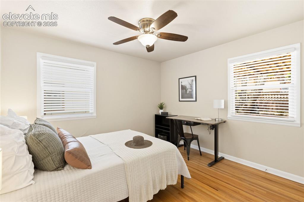 Image 23 of 47: Light-filled room featuring wood-finish flooring and two windows with white