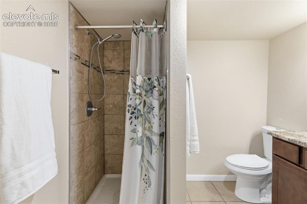 Image 28 of 47: Tiled shower enclosure featuring a handheld showerhead and a decorative acc