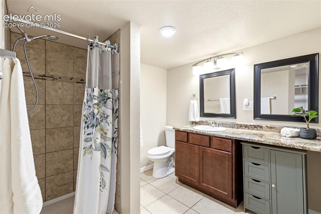 Image 30 of 48: Bathroom featuring a walk-in shower with tiled walls, a dual vanity with a 