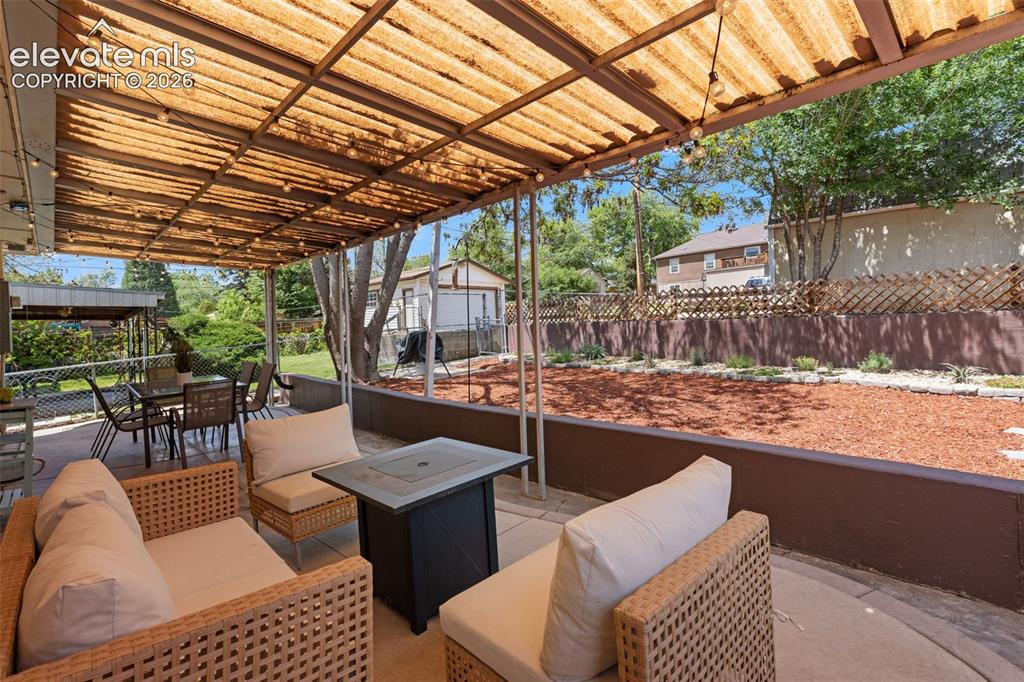Image 36 of 47: Expansive outdoor patio featuring a corrugated translucent roof, string lig