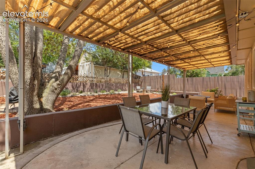 Image 37 of 47: Expansive covered patio featuring a concrete surface, a slatted roof struct