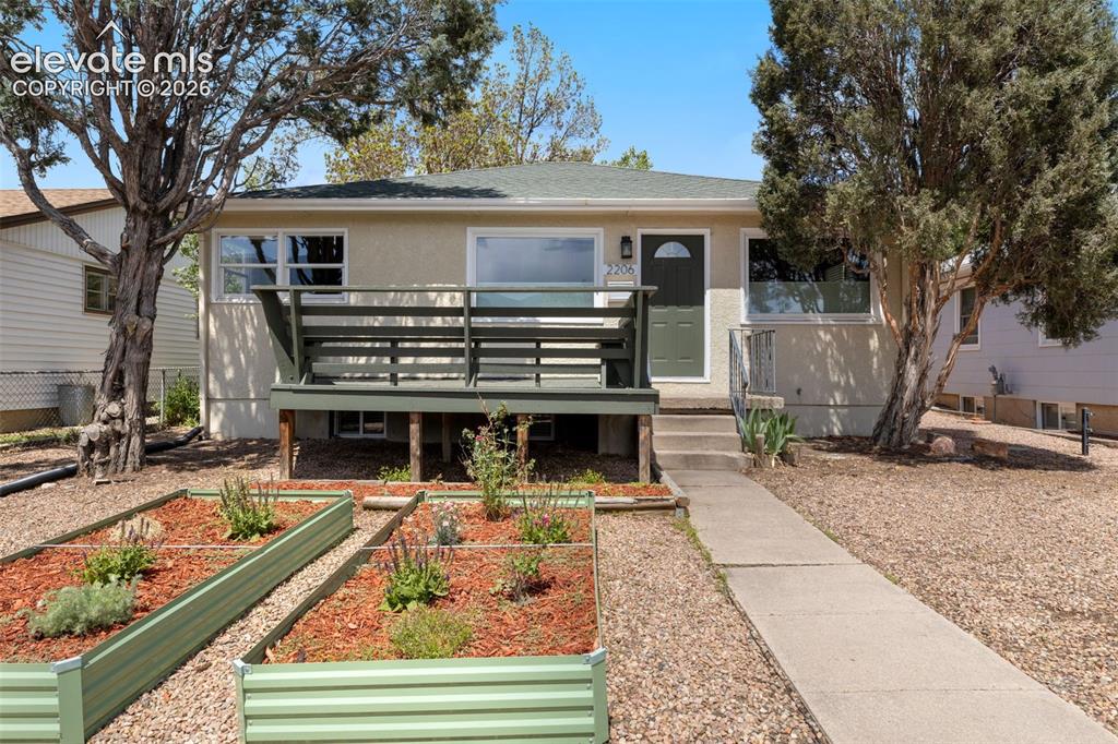 Image 4 of 47: Stucco exterior featuring a dark green entry door with a decorative window