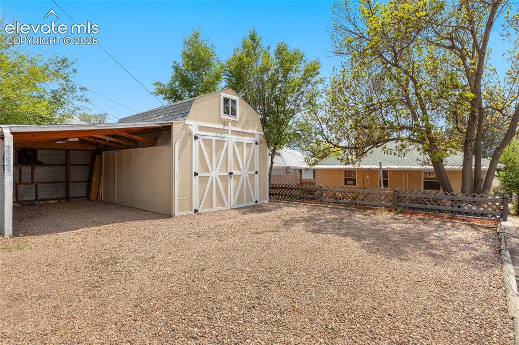 Image 41 of 47: Gravel driveway featuring a detached shed with double barn doors and an att