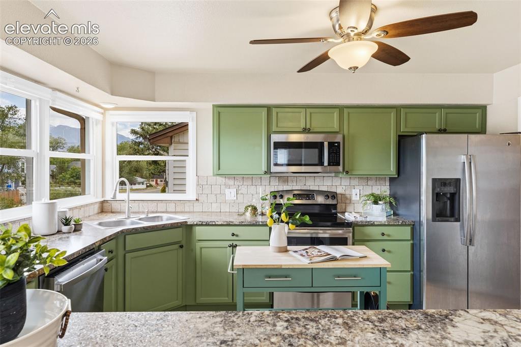 Image 8 of 47: Kitchen featuring green cabinetry, stainless steel appliances, a corner dou