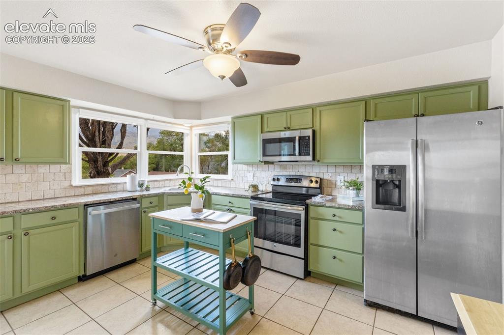 Image 9 of 48: Kitchen featuring stainless steel appliances, abundant cabinetry, a tile ba