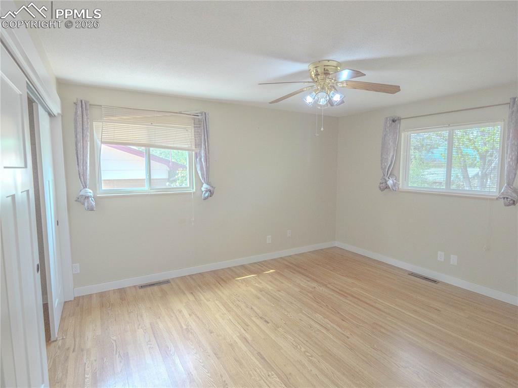 Image 13 of 29: Light-filled room featuring wood-finish flooring, neutral wall paint, and a