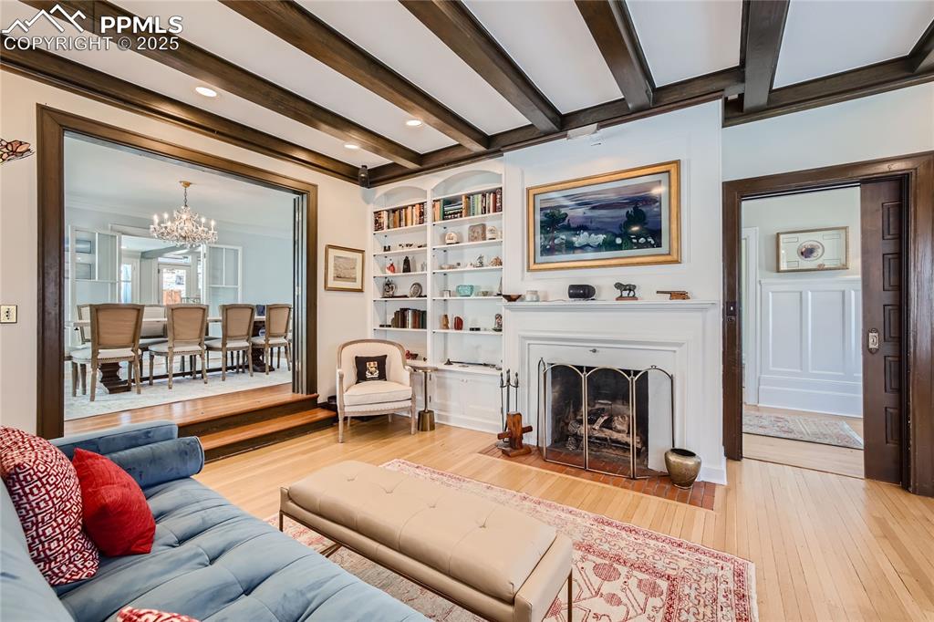 Image 18 of 49: Living room with crown molding, light wood-type flooring, and beamed ceilin