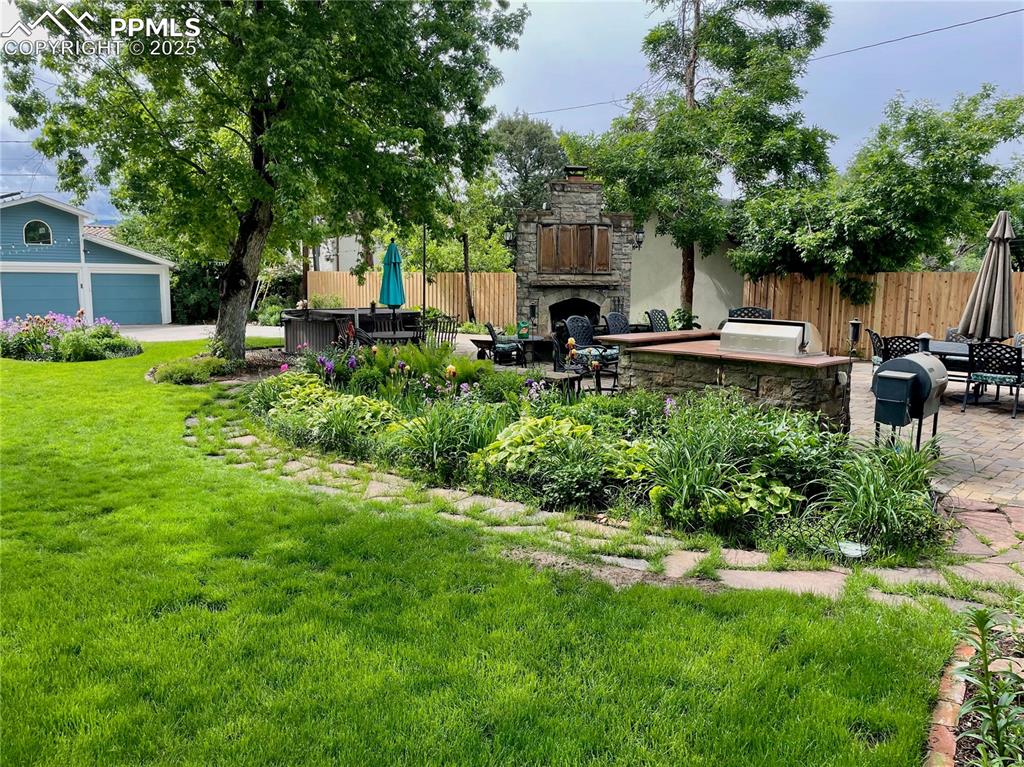 Image 4 of 49: View of yard featuring a patio area, an outdoor stone fireplace, and a gara