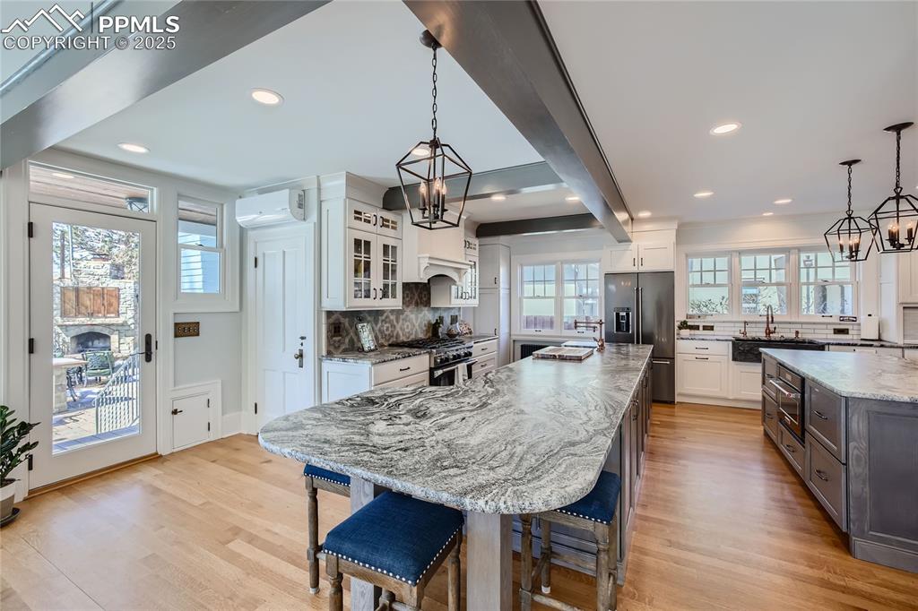 Image 8 of 49: Kitchen with light wood flooring, a center island, high quality appliances,