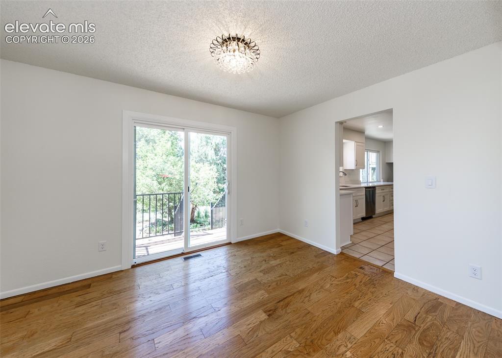 Image 10 of 30: Bright living space featuring wood-finish flooring and a contemporary chand