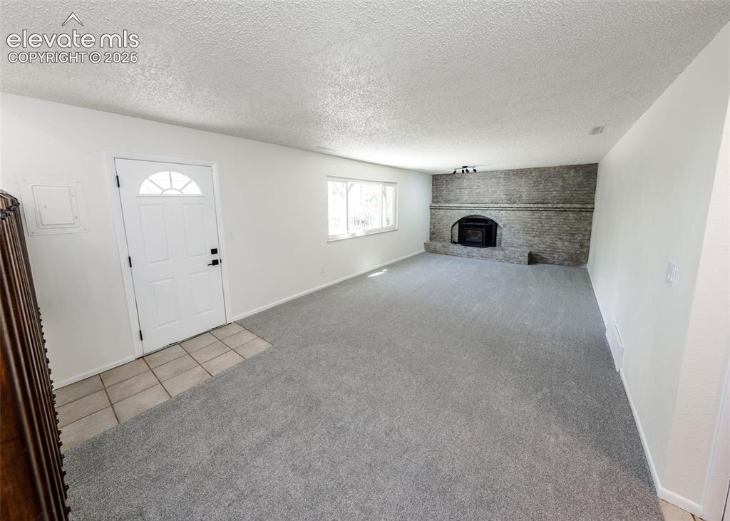 Image 11 of 30: Spacious living area featuring a gray brick fireplace with an insert, light