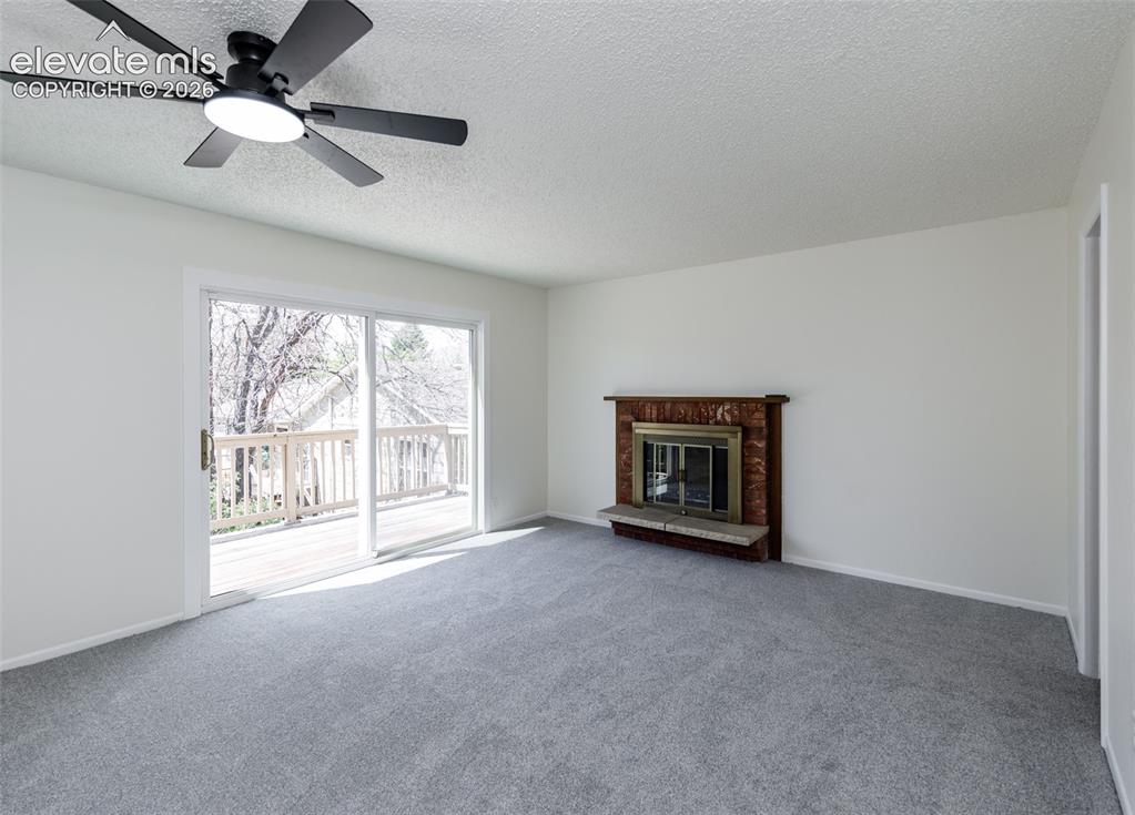 Image 12 of 30: Living space featuring a fireplace with a stone hearth, light gray carpetin