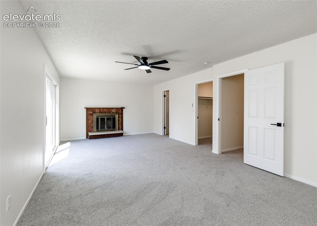 Image 13 of 30: Spacious interior featuring light gray carpet, a brick fireplace with a woo