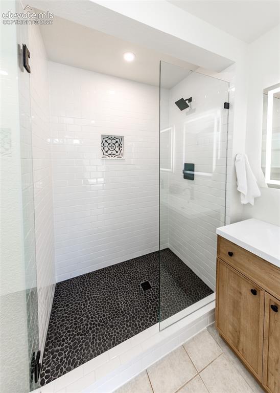 Image 16 of 30: Glass-enclosed shower featuring white subway tile walls, a pebble stone flo