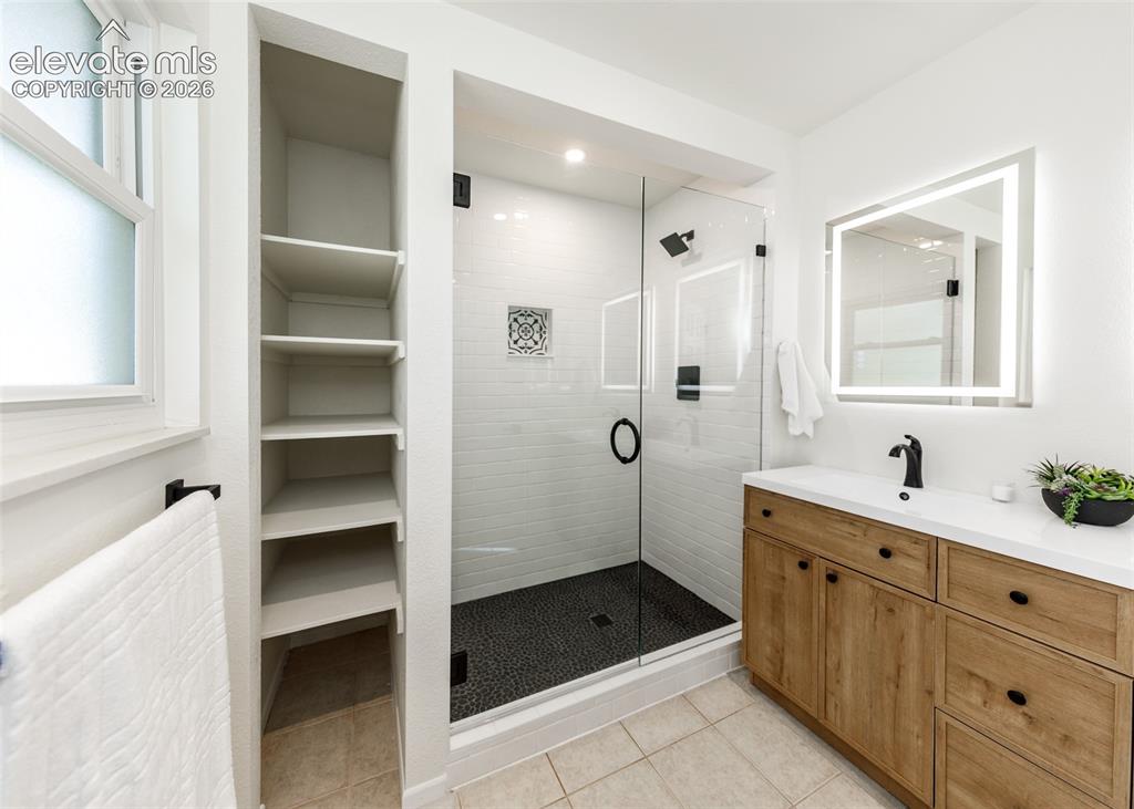 Image 17 of 30: Modern bathroom featuring a glass-enclosed shower with pebble flooring and