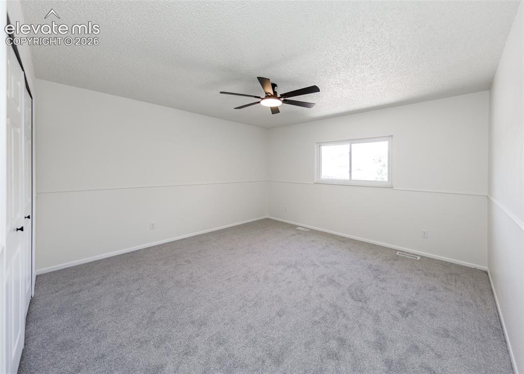 Image 18 of 30: Spacious room featuring neutral carpeting, white walls with wainscoting, an