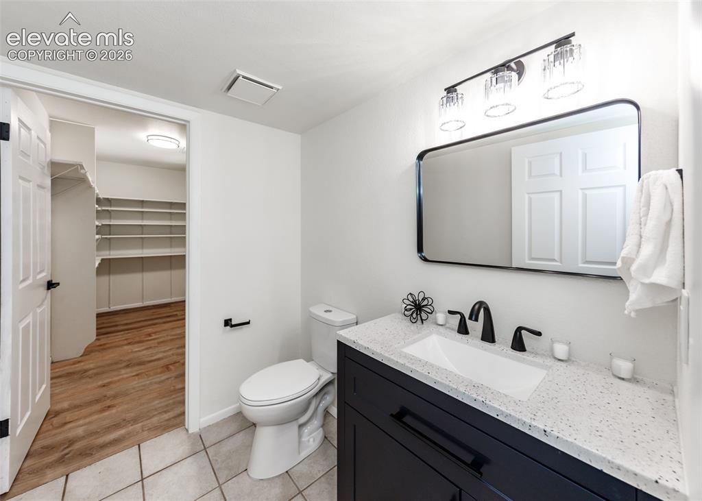 Image 22 of 30: Bathroom featuring a dark wood-finish vanity with a white speckled countert