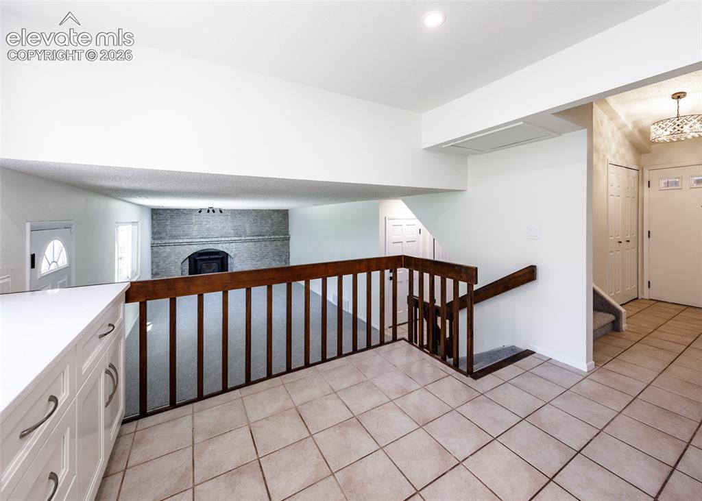 Image 9 of 30: Tiled flooring entrance with a wood-finish staircase railing and a built-in