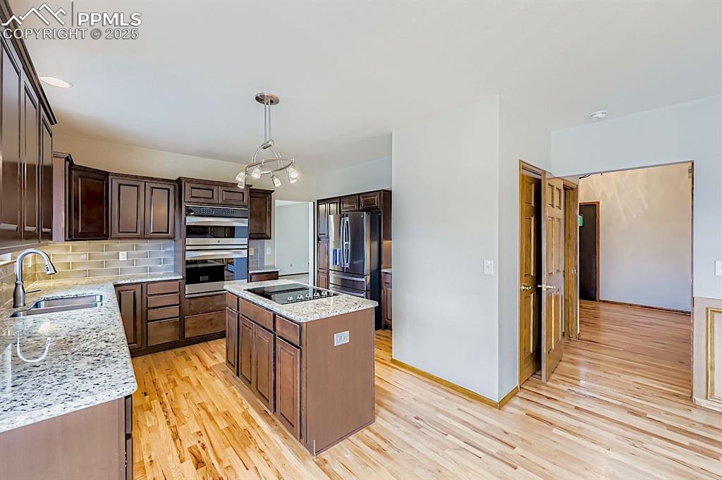 Image 10 of 48: Kitchen featuring backsplash, a kitchen island, light wood-type flooring, l