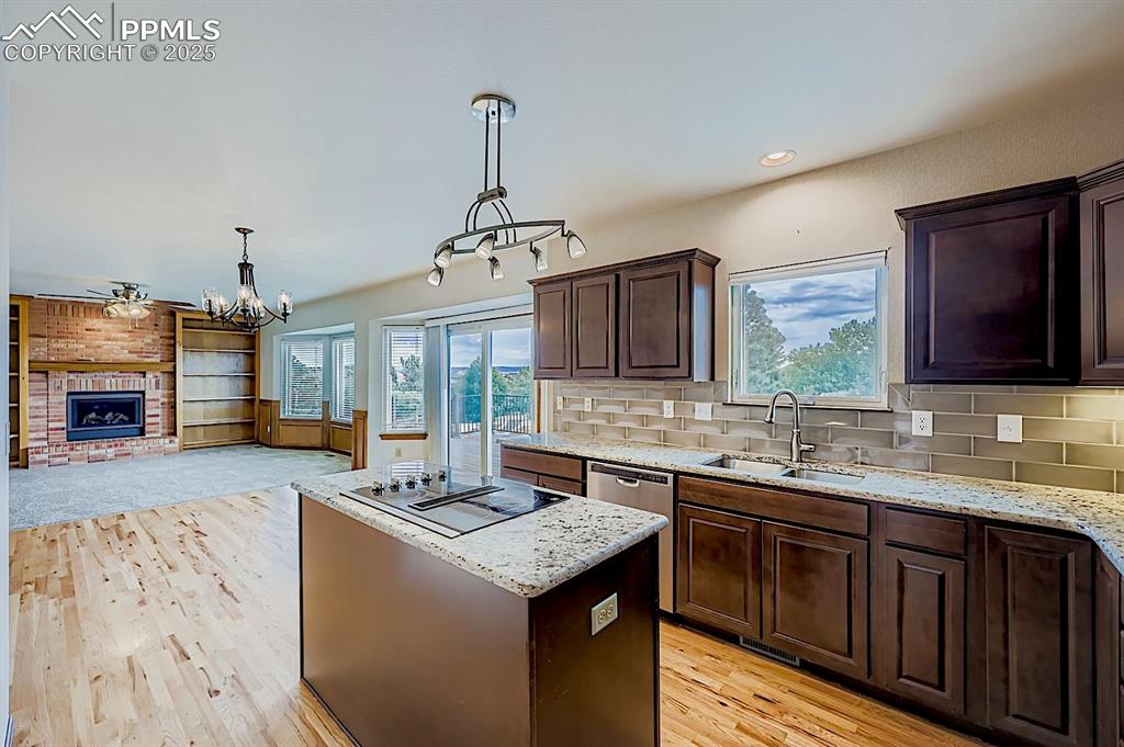 Image 11 of 48: Kitchen featuring a center island, dark brown cabinetry, plenty of natural 