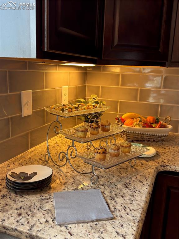 Image 13 of 48: Detailed view of decorative backsplash, dark brown cabinetry, and light sto