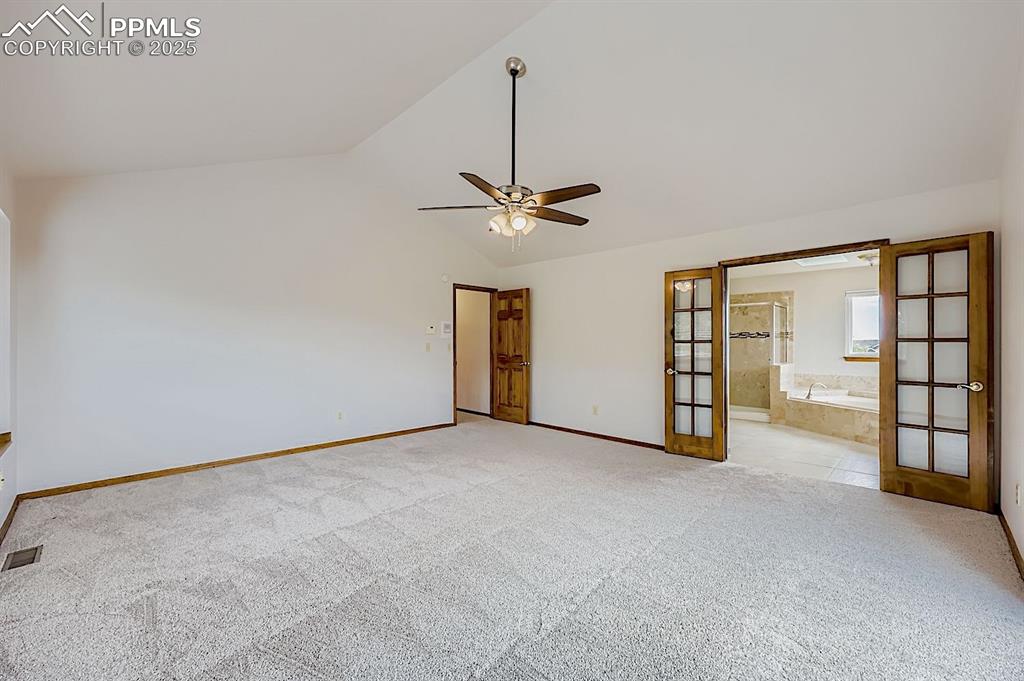 Image 26 of 48: Unfurnished bedroom with vaulted ceiling, ceiling fan, light carpet, french
