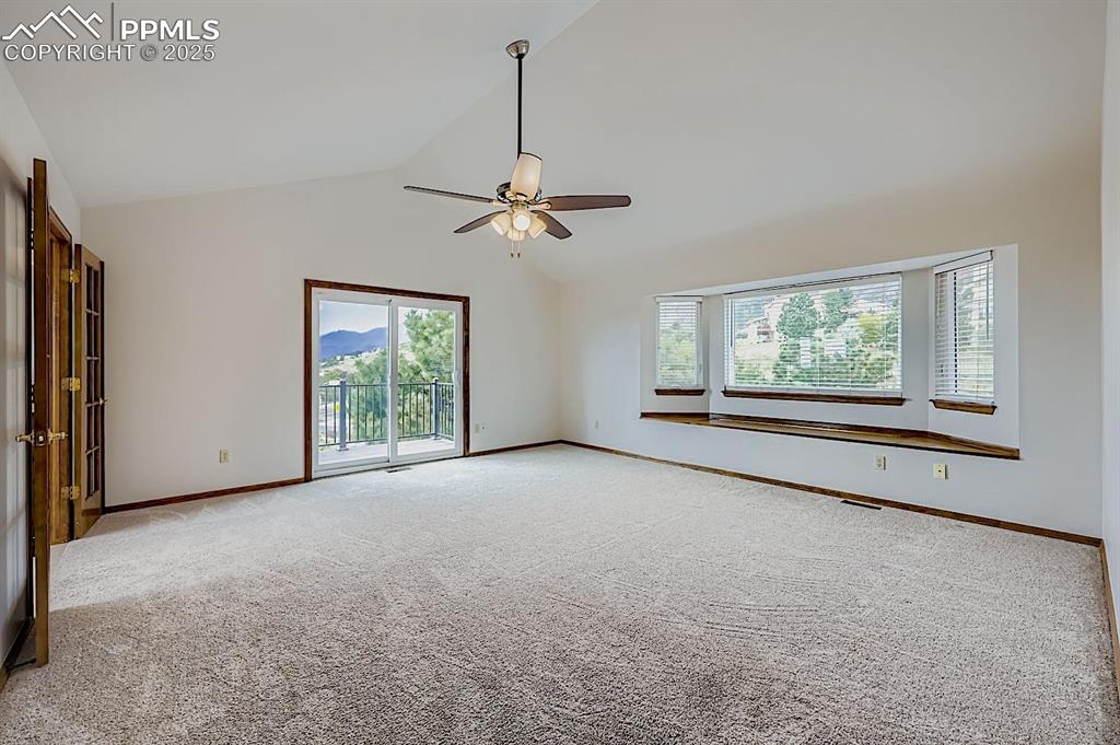 Image 27 of 48: Empty room with light colored carpet, high vaulted ceiling, and ceiling fan