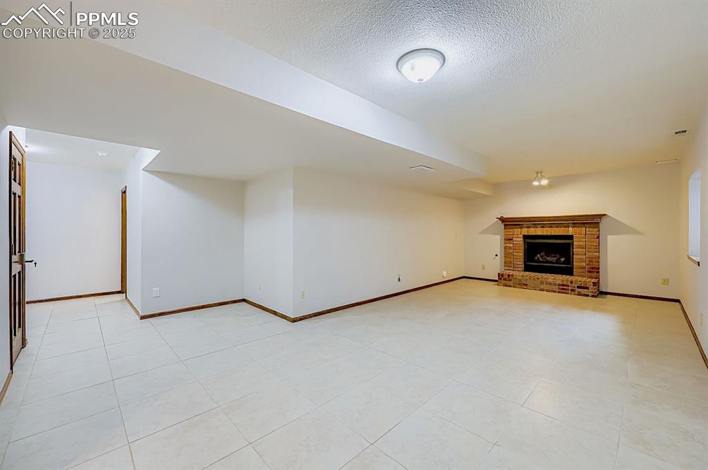 Image 35 of 48: Unfurnished living room with a textured ceiling, a fireplace, and light til