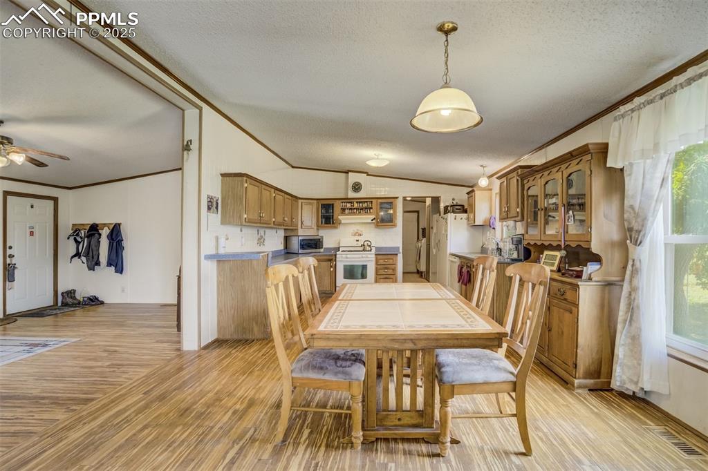 Image 11 of 50: Dining room with ornamental molding, a textured ceiling, light wood-style f