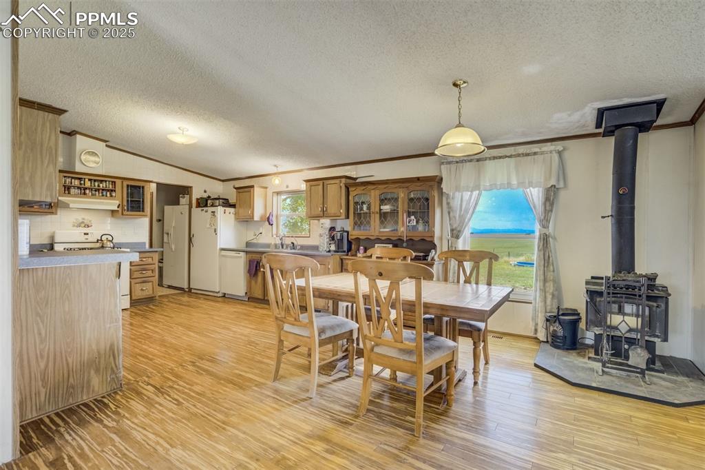 Image 12 of 50: Dining area featuring a wood stove, ornamental molding, a textured ceiling,